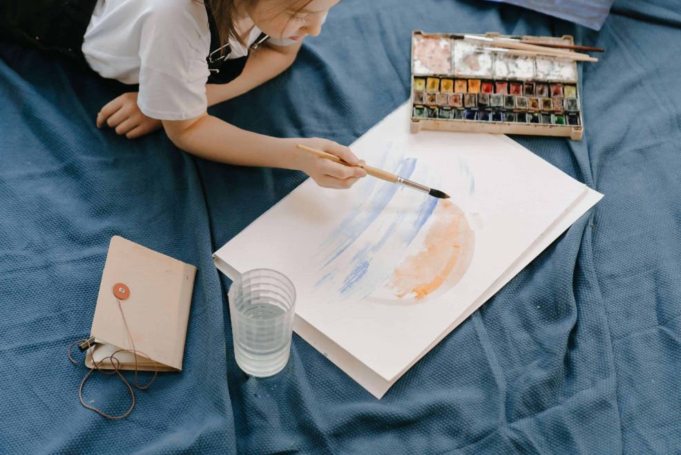 3. Activități cu copii în casă - îmbogățește rutina copilului tău prin creativitate și învățare - fată care pictează, pătură albastră, acuarele