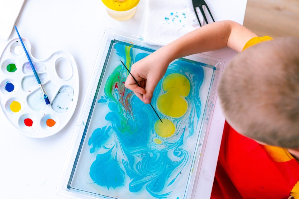 2.2. Idei creative de pictura abstracta - copil picteaza cu galben pe fundal albastru